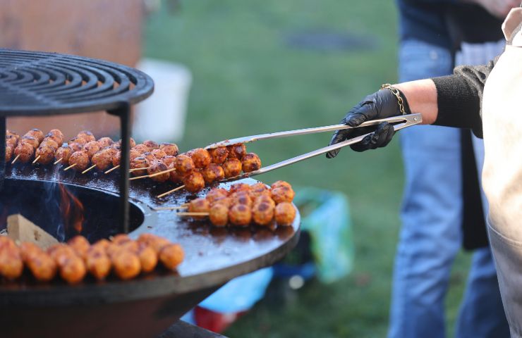 uomo al barbecue mentre cuoce polpette
